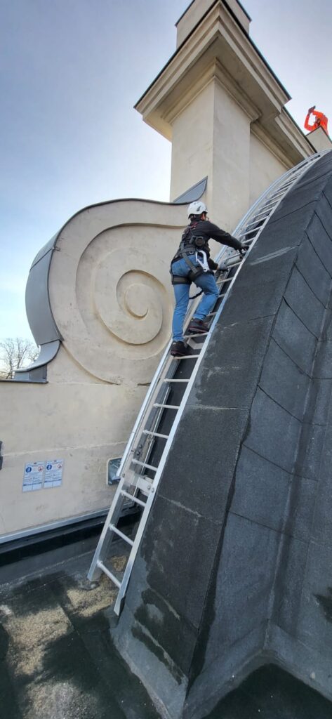 Man using rope access and safety harness, climbing a safety ladder on a listed building. 
